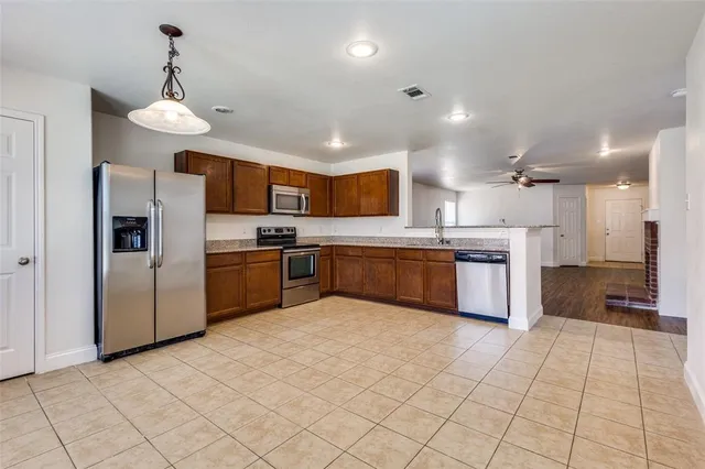 a large kitchen with stainless steel appliances kitchen island granite countertop a stove a sink dishwasher and a refrigerator