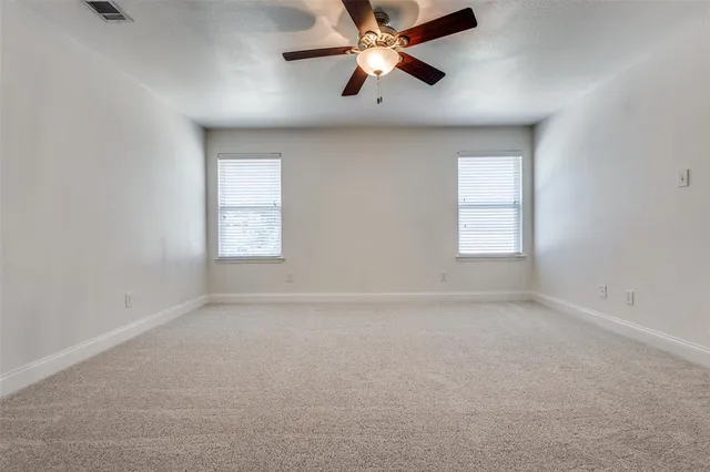 an empty room with a window and a fan