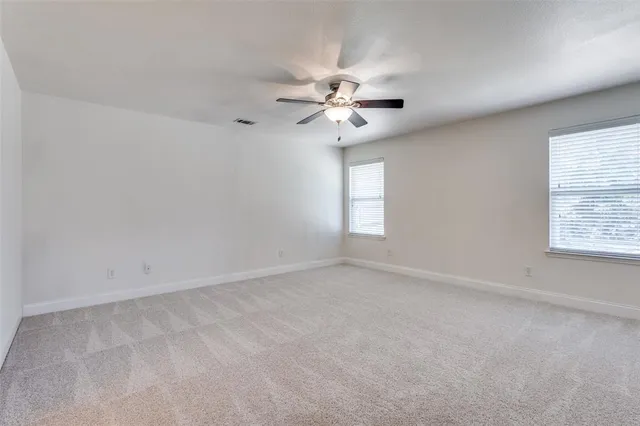 an empty room with windows and fan