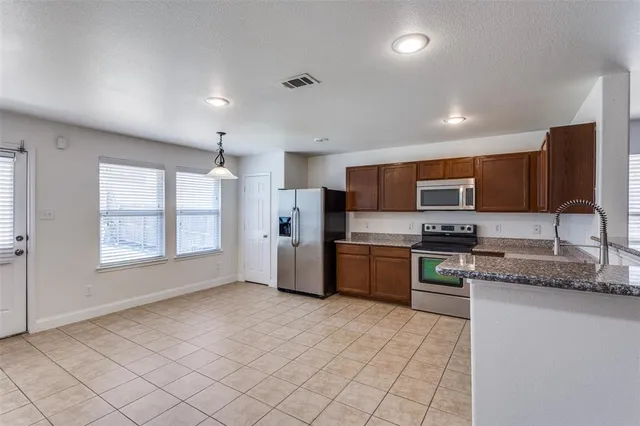 a kitchen with stainless steel appliances granite countertop a stove a sink and a refrigerator