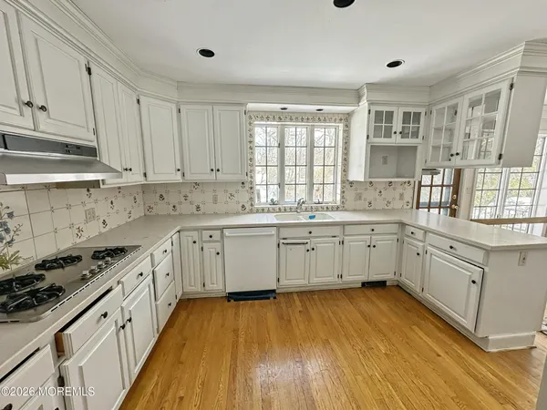 a large white kitchen with wooden floors and white stainless steel appliances