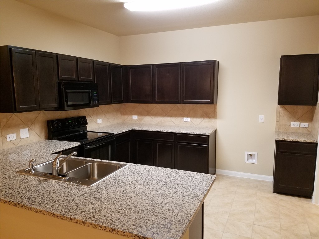 5905 Montrelia Drive Austin, TX 78724 - Photo 6 of 25 a kitchen with granite countertop a stove and a microwave