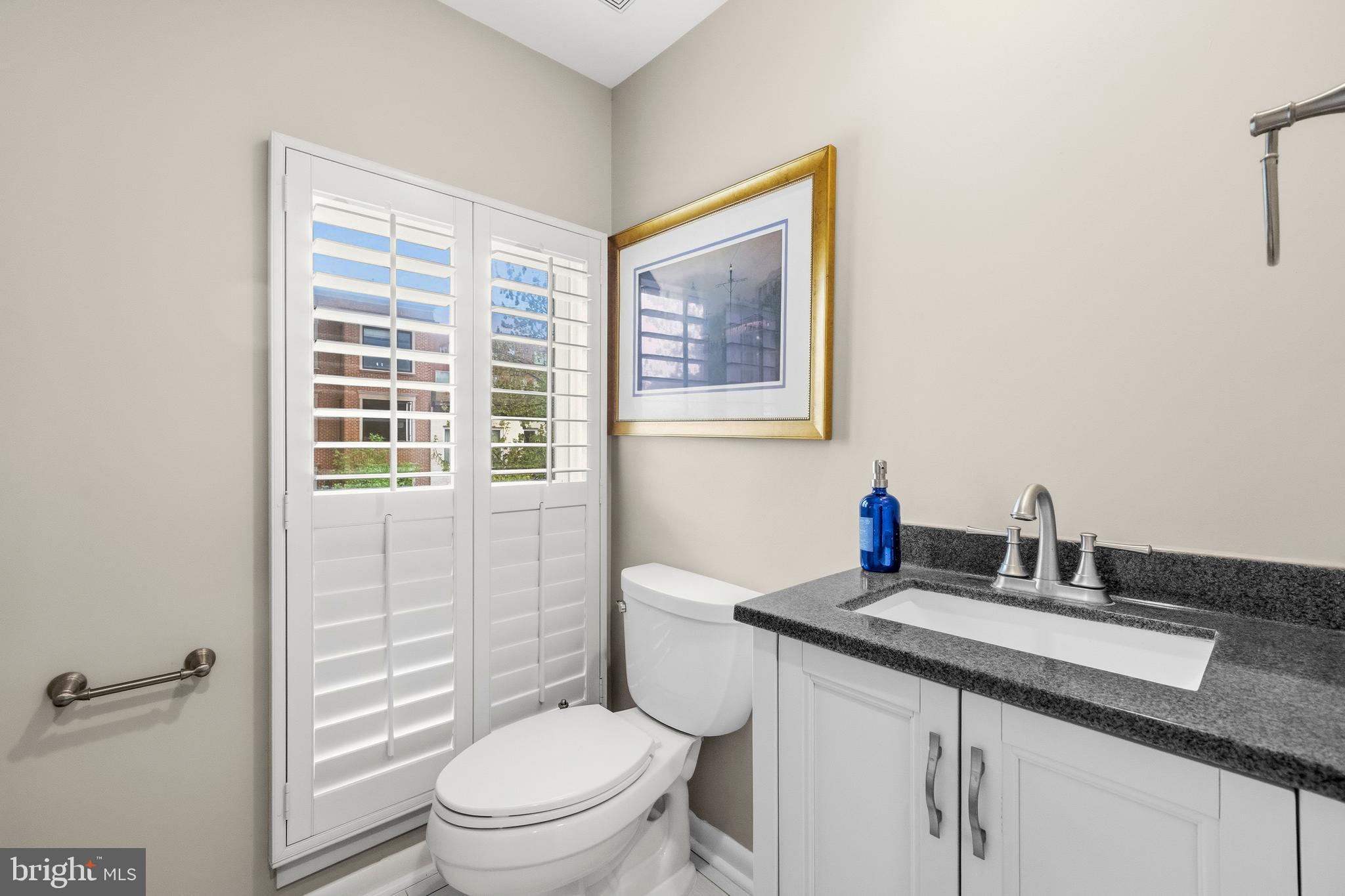 2116 12th Street Northwest Washington, DC 20009 - Photo 13 of 35 a bathroom with a granite countertop toilet a sink and a mirror