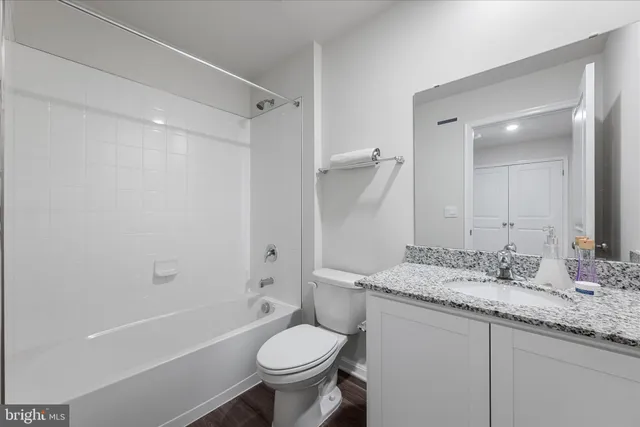 a bathroom with a granite countertop sink toilet mirror and bathtub
