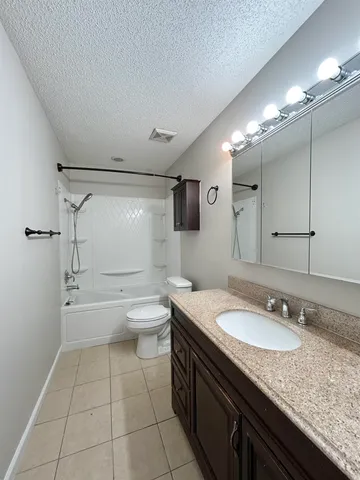 a bathroom with a granite countertop sink a toilet a mirror and shower