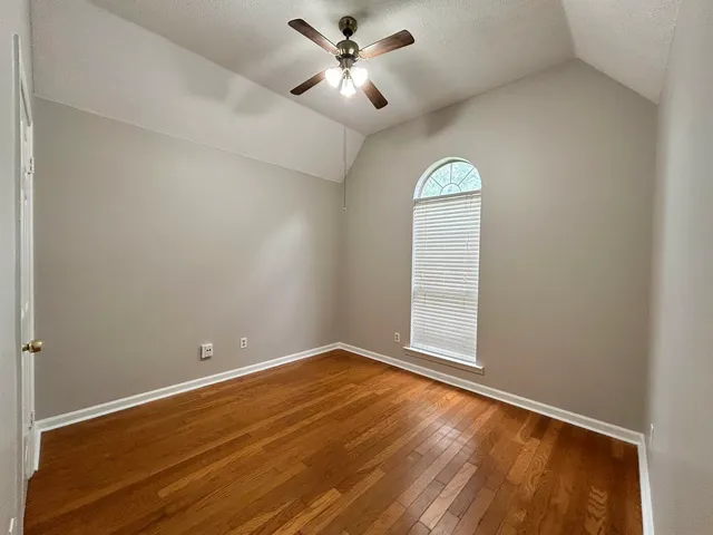 a view of empty room with wooden floor and fan