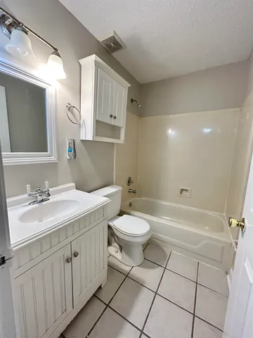 a bathroom with a toilet a sink a mirror a bathtub and vanity