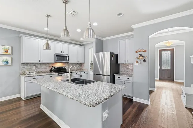 a kitchen with stainless steel appliances granite countertop a refrigerator a stove a sink dishwasher and a refrigerator with wooden floor