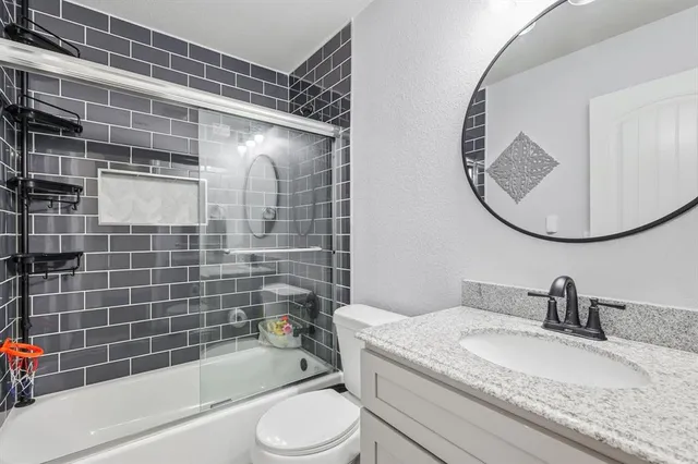 a bathroom with a granite countertop bathtub sink vanity mirror and toilet