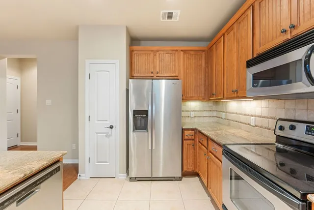 a large kitchen with stainless steel appliances granite countertop a stove and a refrigerator