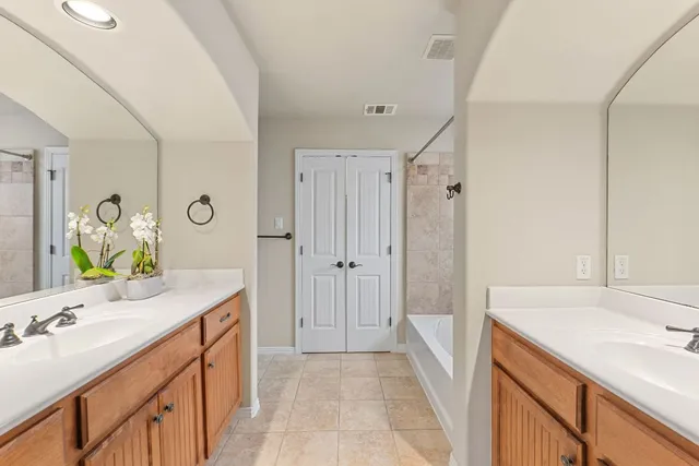 a bathroom with a sink vanity granite tub shower and mirror