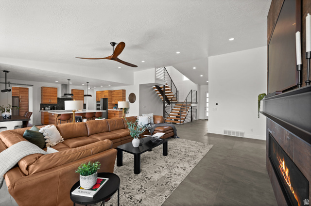 507 West Windmill Gate Cove Draper, UT 84020 - Photo 8 of 46 Living room featuring a textured ceiling, concrete floors, a ceiling fan, recessed lighting, and a lit fireplace
