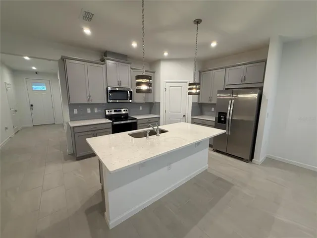 a large kitchen with stainless steel appliances kitchen island granite countertop a refrigerator a stove a sink a microwave a island and a refrigerator