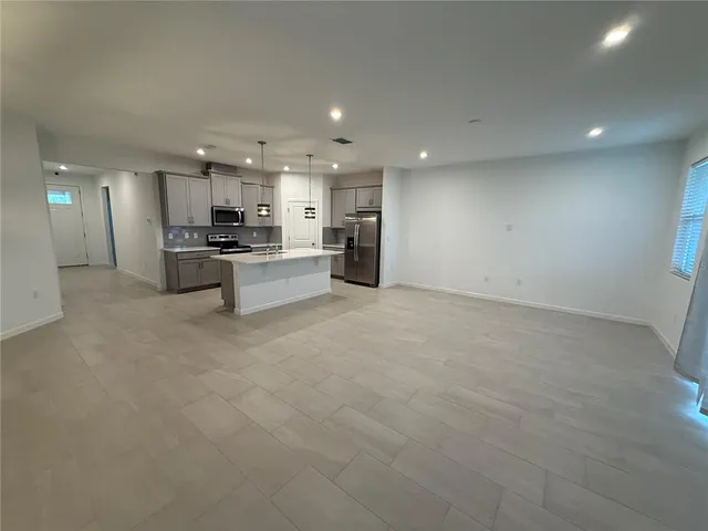 a view of a kitchen with kitchen island a sink stainless steel appliances and cabinets