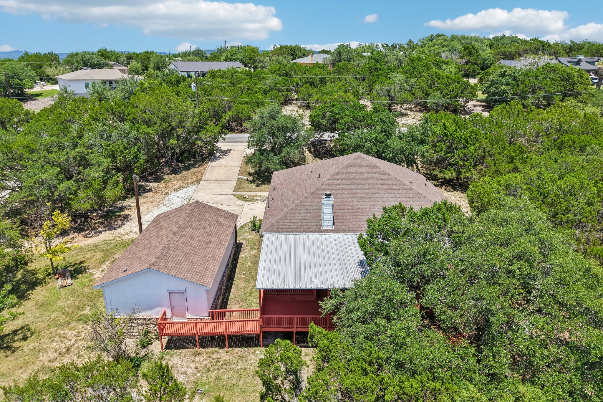 20609 Bridle Path Road Lago Vista, TX 78645 - Photo 21 of 30 An aerial perspective reveals a private home nestled amidst a verdant landscape, featuring an inviting red-decked patio.