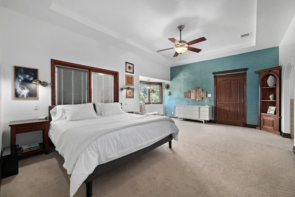 2001 Mestena Trail Austin, TX 78733 - Photo 30 of 40 a spacious bedroom with a large bed and a chandelier