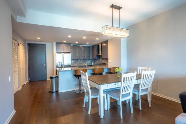 a view of a dining room with furniture wooden floor kitchen and chandelier
