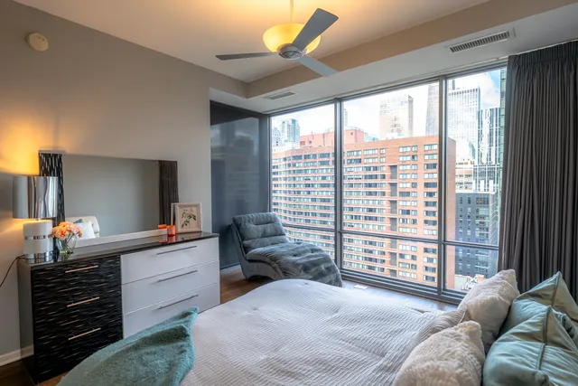 a bedroom with a bed a flat screen tv and a large window with balcony view