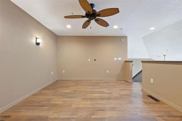 an empty room with wooden floor and a ceiling fan