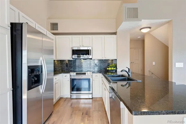 a kitchen with kitchen island granite countertop a sink stainless steel appliances and cabinets