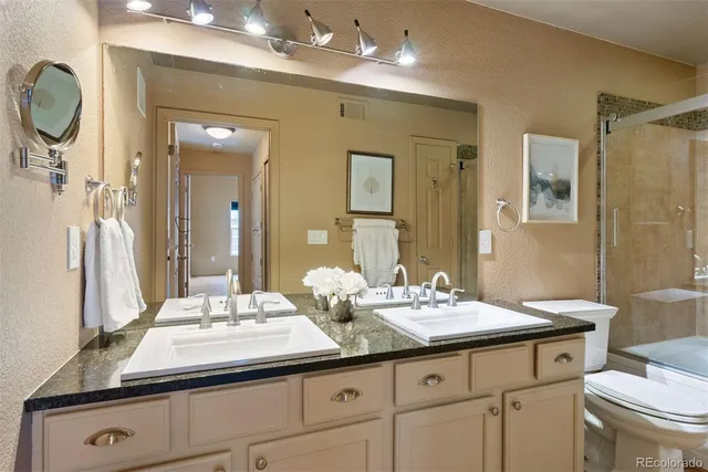 a bathroom with a granite countertop sink a toilet and a mirror
