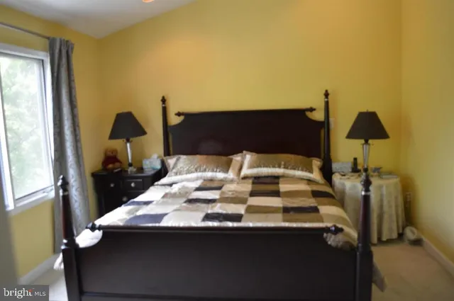 a bedroom with a bed and lamp on dresser