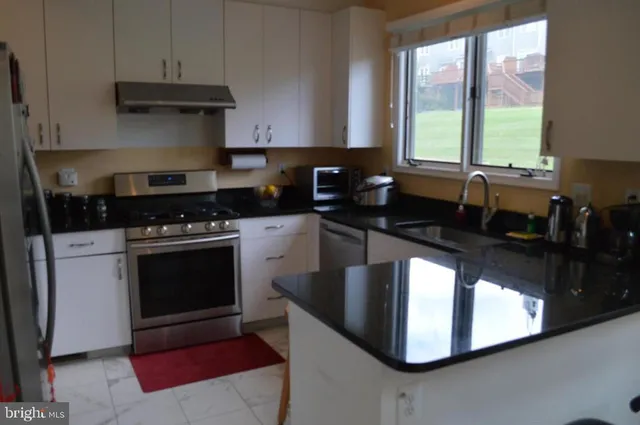 a kitchen with stainless steel appliances granite countertop a stove a sink and a microwave