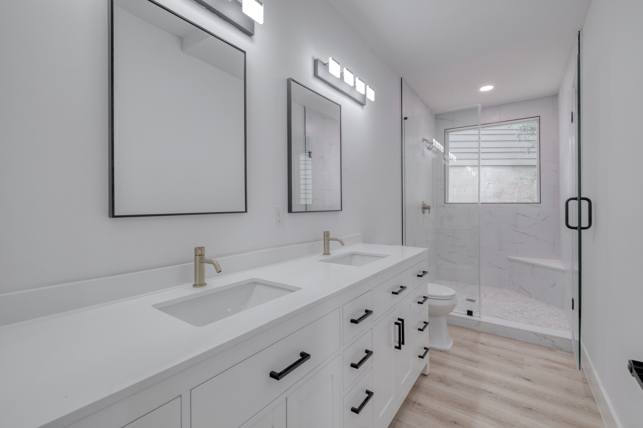 5211 Rob-Scott Street Austin, TX 78721 - Photo 16 of 24 A well-lit primary bathroom features a dual vanity, a glass-enclosed shower, and sleek modern fixtures.