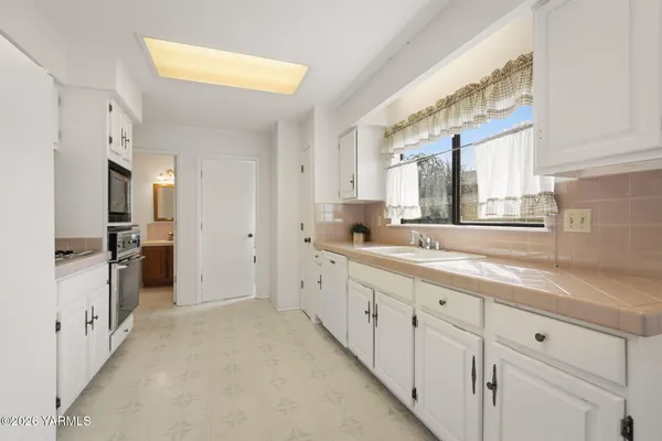 a large white kitchen with a sink and refrigerator