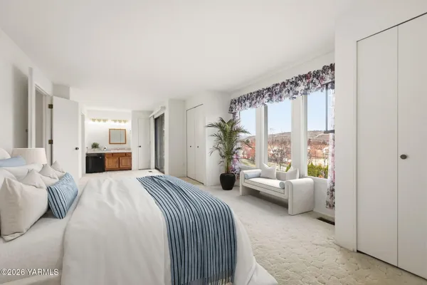 a bedroom with a bed and large windows