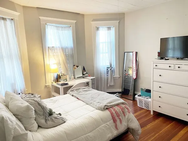 a bedroom with a bed and a flat tv screen on dresser