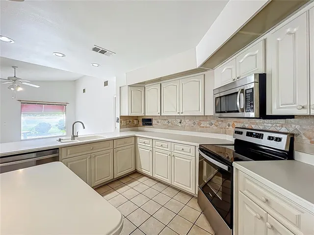 a kitchen with cabinets appliances a sink and a window