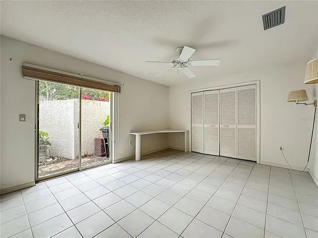 a view of an empty room with window and chandelier fan
