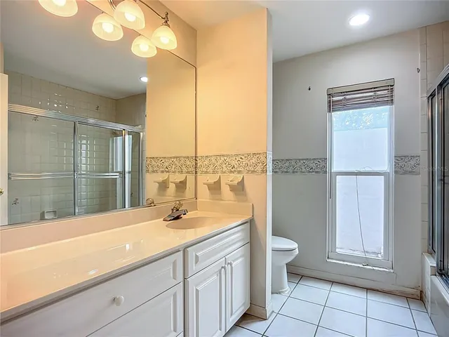 a bathroom with a granite countertop bathtub shower and toilet