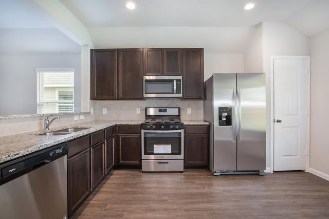 a kitchen with granite countertop a stove and a refrigerator
