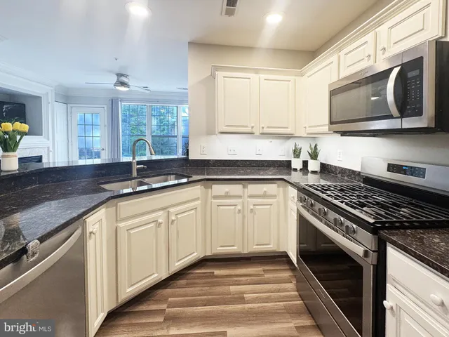 a kitchen with granite countertop a sink stainless steel appliances and cabinets