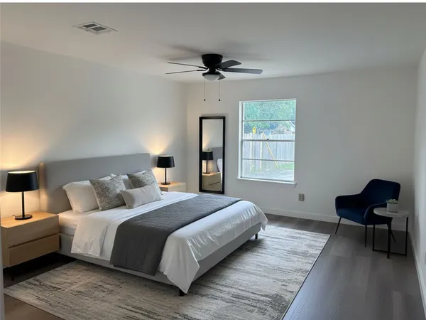 a bedroom with a bed wooden floor and a chair