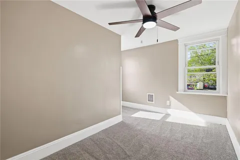 an empty room with windows and fan