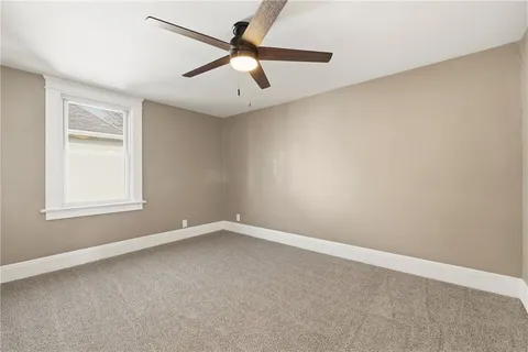 an empty room with a ceiling fan and a window