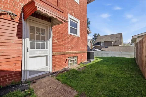 a front view of house with yard and trees in the background