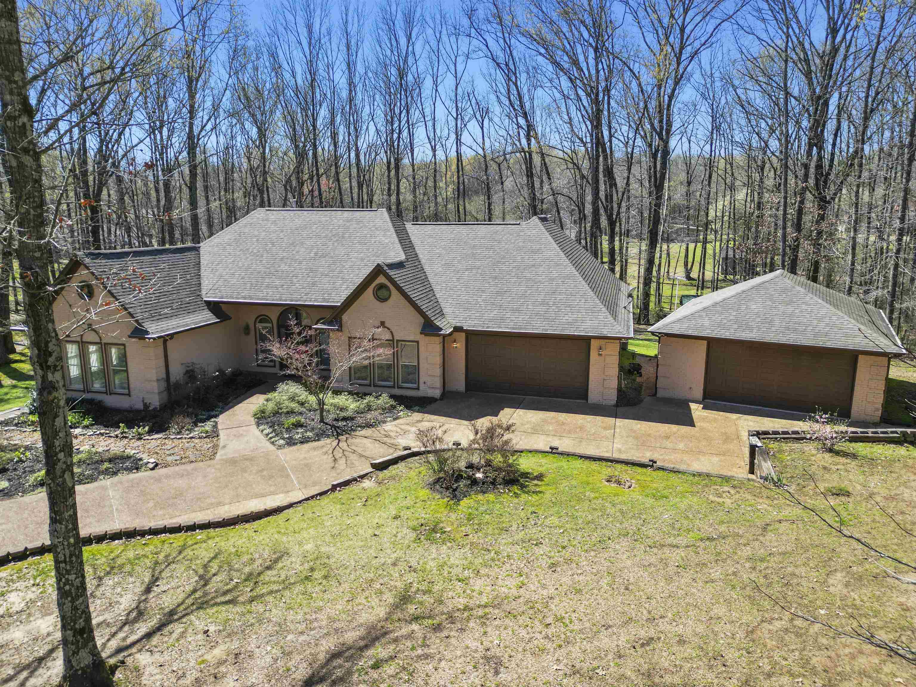 View of front of property with a shingled roof, a front lawn, and a detached garage