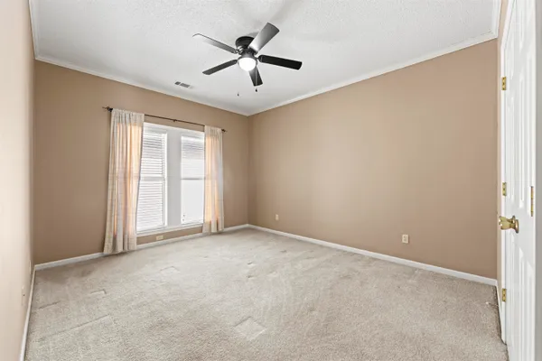 an empty room with ceiling fan and windows