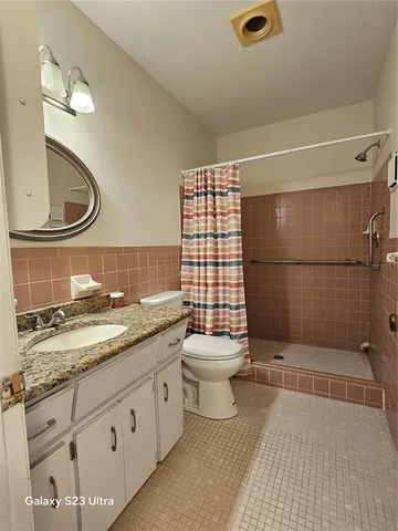 a bathroom with a granite countertop sink toilet and shower