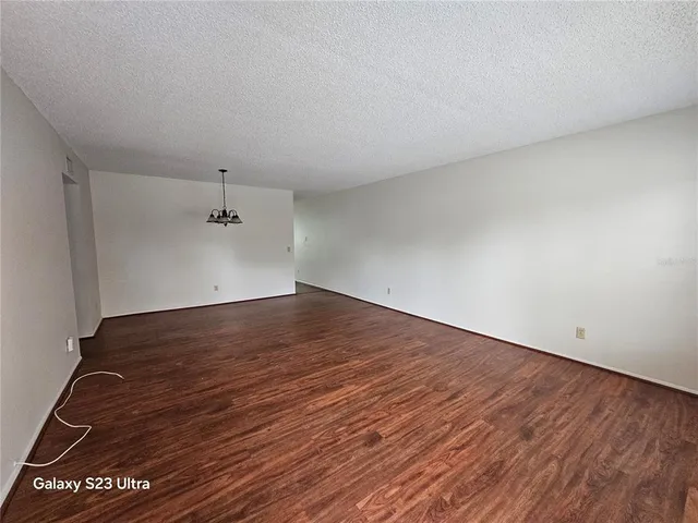 a view of a room with wooden floor chandelier and windows