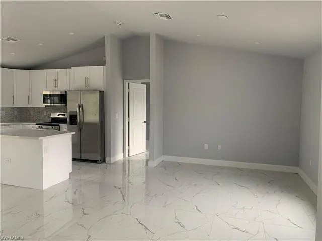 a kitchen with a refrigerator a stove top oven and white cabinets