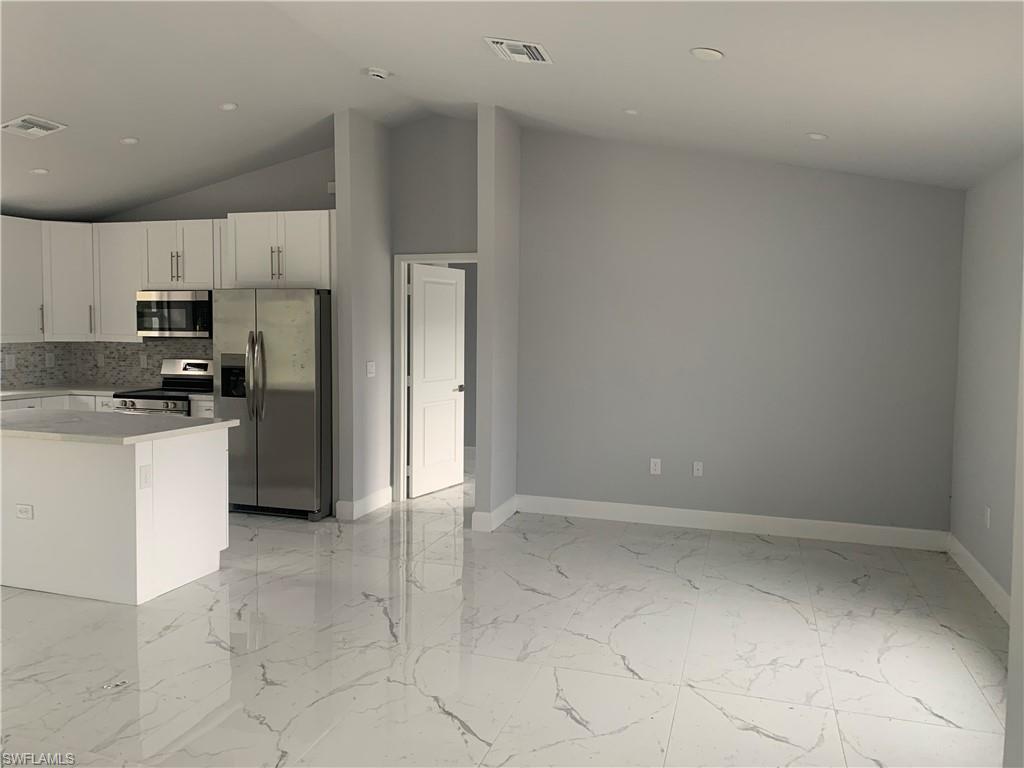 a kitchen with a refrigerator a stove top oven and white cabinets