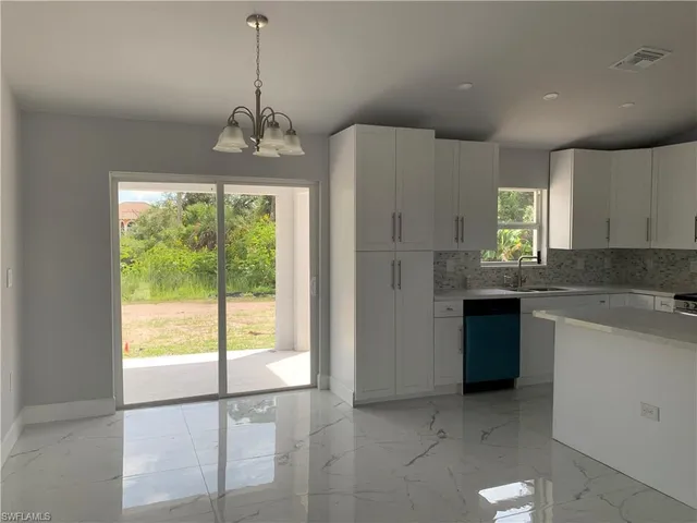 a kitchen with kitchen island granite countertop a stove a sink cabinetry and a chandelier
