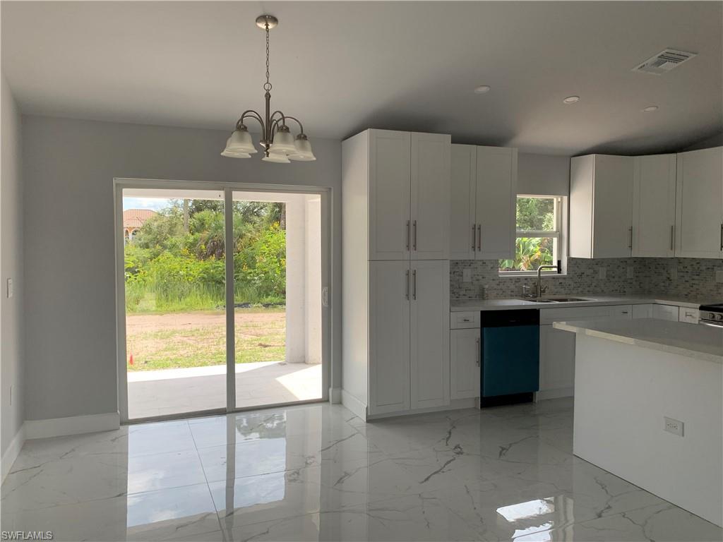 3211 43rd Street Southwest Lehigh Acres, FL 33976 - Photo 18 of 18 a kitchen with kitchen island granite countertop a stove a sink cabinetry and a chandelier
