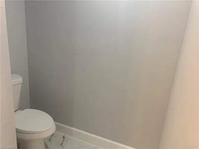 a white toilet sitting next to a white wall