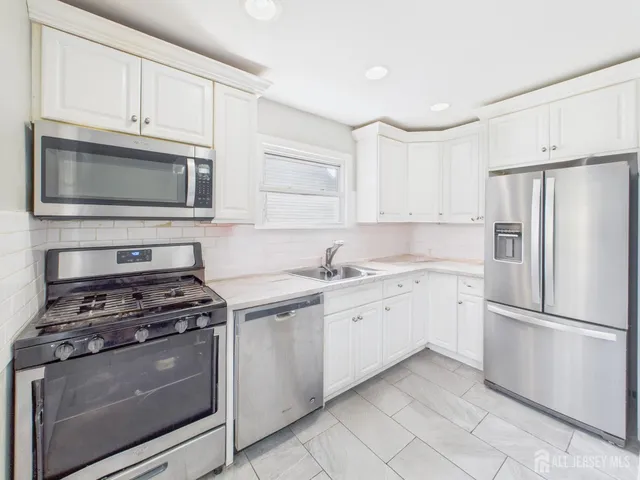 a kitchen with cabinets stainless steel appliances and sink